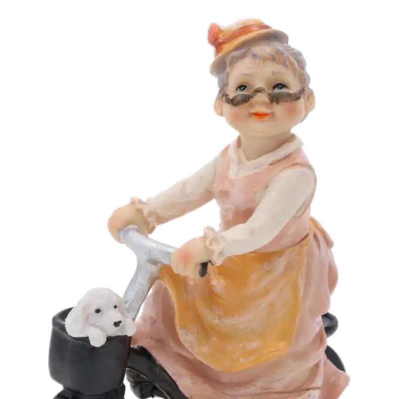 Zbliżenie na górną część figurki: babcię jadącą na rowerze. Widać szczegółowo wykonaną twarz, okulary oraz pieska w koszyku.