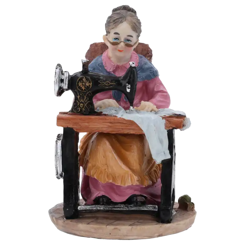 Figurka babcia przy maszynie do szycia o wysokości 17 cm. Estetyczna dekoracja z tworzywa, która świetnie pasuje jako element stroików lub upominek okolicznościowy.