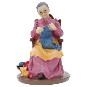 Figurka babcia robiąca na drutach o wysokości 17 cm, wykonana z tworzywa, przedstawia postać w fotelu z robótką ręczną. Idealna dekoracja na Dzień Babci i Dziadka.