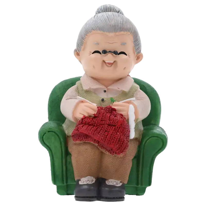 Figurka babcia robiąca na drutach o wysokości 11 cm. Sympatyczna staruszka w zielonym fotelu z robótką w rękach. Idealna jako ozdoba tortu lub prezent.