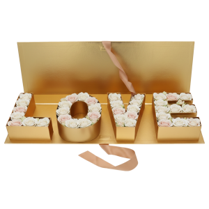 Złoty flowerbox LOVE wypełniony jasnymi różami, tworzący gotową kompozycję prezentową o szerokości 65 cm.