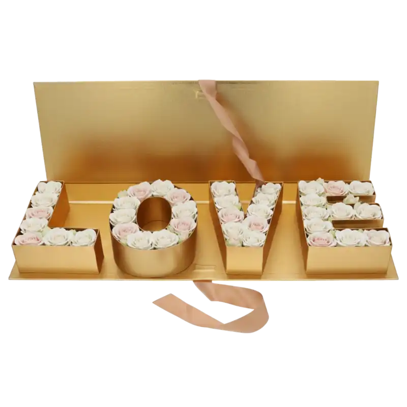 Złoty flowerbox LOVE wypełniony jasnymi różami, tworzący gotową kompozycję prezentową o szerokości 65 cm.