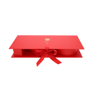Złożone czerwone pudełko prezentowe ze złotym nadrukiem róży i napisem For You na wieczku, przewiązane wstążką.