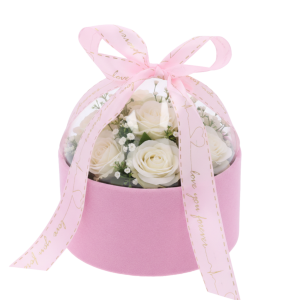 Różowy welurowy flower box 13 cm z kompozycją z białych róż oraz gipsówki pod przezroczystą pokrywą.