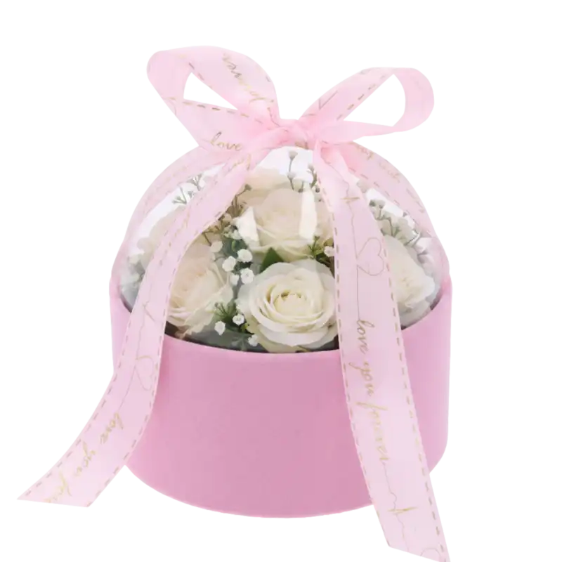 Różowy welurowy flower box 13 cm z kompozycją z białych róż oraz gipsówki pod przezroczystą pokrywą.