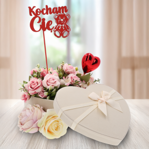 Topper z napisem Kocham Cię umieszczony w dekoracyjnym flowerboxie z kwiatami. Czerwony akcent doskonale komponuje się z romantycznym charakterem kompozycji.