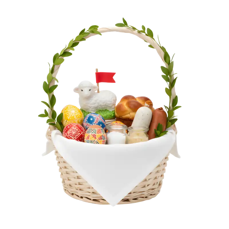 Wiklinowy koszyk wypełniony wielkanocnymi produktami: pisankami, barankiem z flagą, wędlinami i babką. Naturalna dekoracja świątecznego stołu.