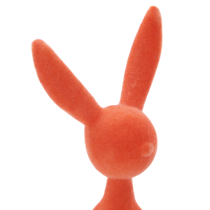 Szczegółowe ujęcie górnej partii pomarańczowej figurki zająca z weluru. Widoczna nowoczesna forma i miękkie wykończenie powierzchni.