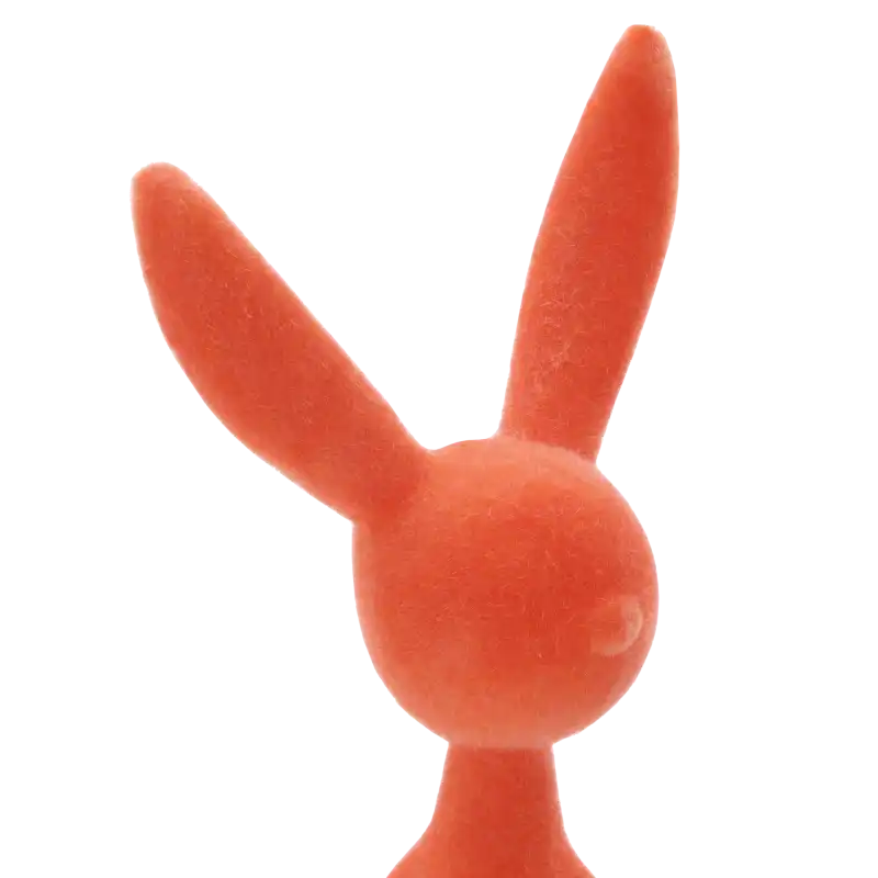 Szczegółowe ujęcie górnej partii pomarańczowej figurki zająca z weluru. Widoczna nowoczesna forma i miękkie wykończenie powierzchni.