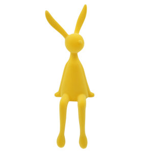 Ujęcie profilowe żółtej figurki zająca, prezentujące smukłą linię i stabilną pozycję siedzącą w nowoczesnym stylu.