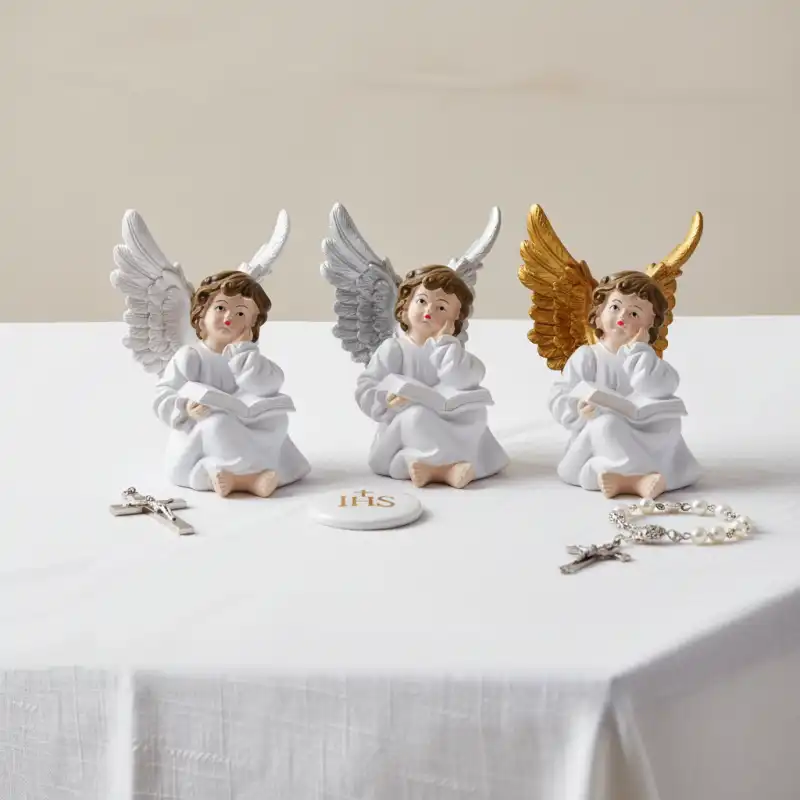 Zestaw trzech aniołków o wysokości 14 cm na białym stole. Dekoracja uzupełniona elementami komunijnymi takimi jak krzyżyk i różaniec.