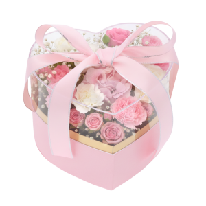 Różowy flower box w kształcie serca wypełniony kompozycją z różowych i białych róż oraz zielonych liści.
