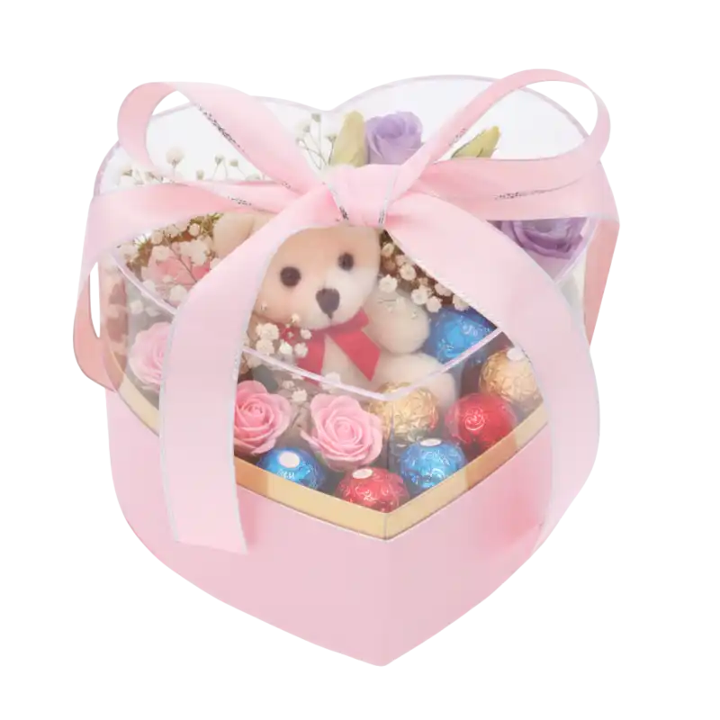 Flower box serce 15x14x12 cm z misiem, czekoladkami i kwiatami, zapakowany w przezroczyste pudełko z kokardą.
