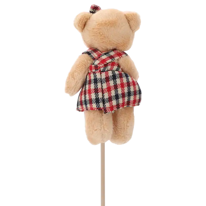 Tylna perspektywa figurki misia na piku, ukazująca sposób wykończenia sukienki z szelkami oraz stabilne mocowanie na patyczku.
