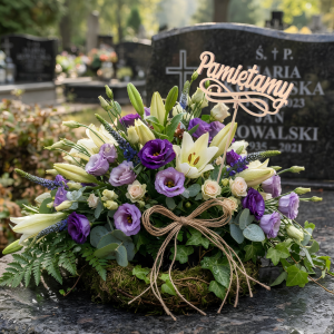 Topper Pamiętamy umieszczony w okazałej kompozycji kwiatowej na nagrobku. Drewniana dekoracja wzbogaca bukiet ze stroikiem.