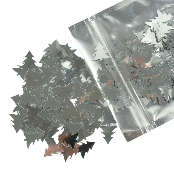 Srebrne confetti w kształcie choinek o rozmiarze ok 2 cm. Opakowanie zawiera 36 g błyszczących ozdób świątecznych.