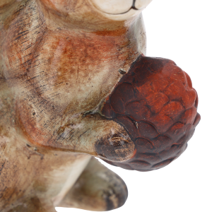 Makro detal ceramicznej figurki wiewiórki, skupienie na fakturze szyszki trzymanej w łapkach zwierzęcia.