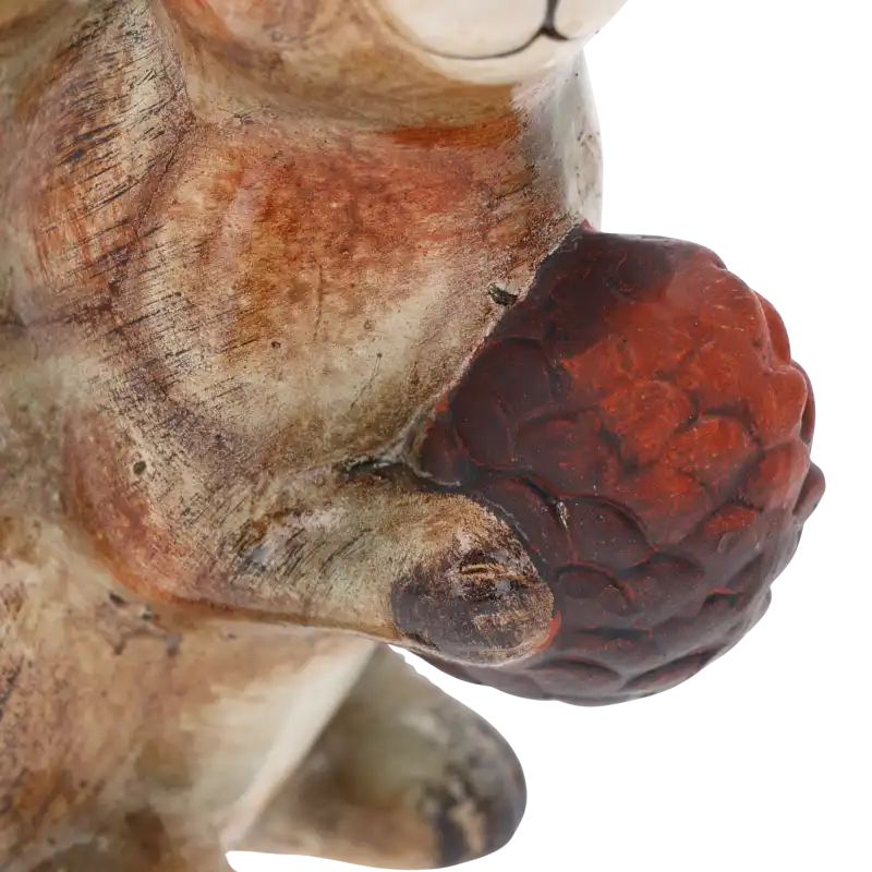 Makro detal ceramicznej figurki wiewiórki, skupienie na fakturze szyszki trzymanej w łapkach zwierzęcia.