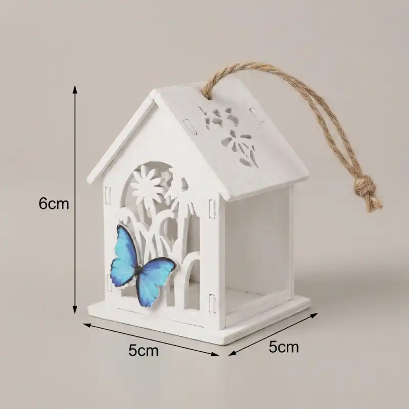 Prezentacja wymiarów białego domku zawieszki z niebieskim motylem. Widać wysokość 7 cm oraz szerokość 5 cm, co ułatwia dopasowanie dekoracji w aranżacji wnętrz.