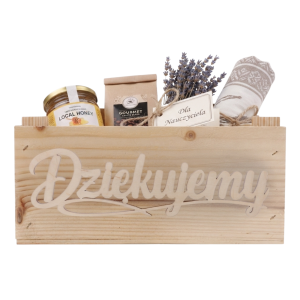 Drewniana skrzynka wypełniona prezentami, w tym miodem, kawą i lawendą, przygotowana jako upominek.