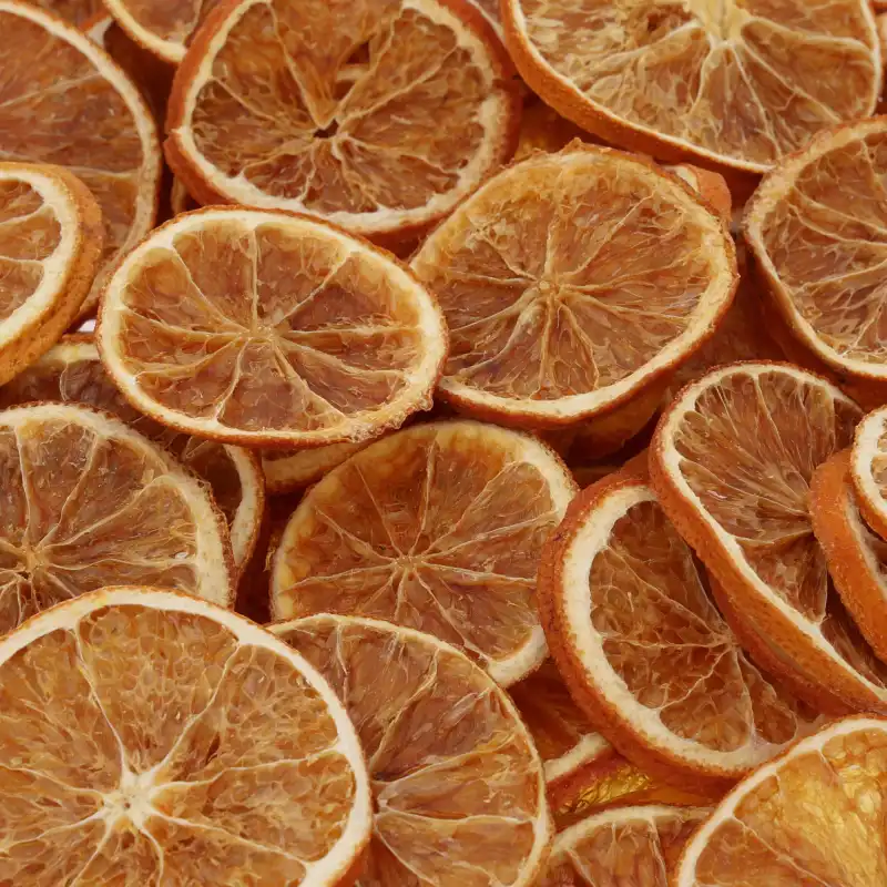 Zbliżenie na naturalną strukturę ułożonych blisko siebie suszonych plastrów pomarańczy Trend Deco w ciepłych barwach