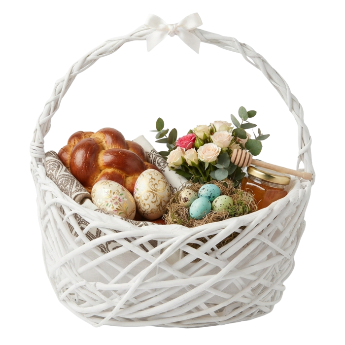 Biały kosz wiklinowy 43 cm wypełniony wielkanocnymi pisankami, babką, miodem i kwiatami jako stroik.