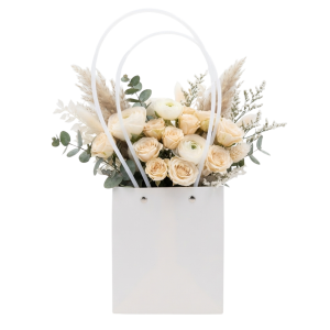 Biała papierowa torebka na kwiaty 36 cm z eleganckim bukietem jasnych róż i dodatków florystycznych.