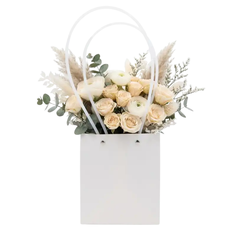 Biała papierowa torebka na kwiaty 36 cm z eleganckim bukietem jasnych róż i dodatków florystycznych.