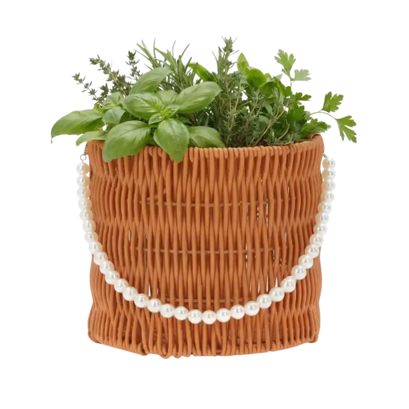 Okrągły brązowy koszyk 16x16x15 cm z plecionki ozdobiony sznurkiem perełek, wypełniony świeżymi ziołami jako domowy zielnik.