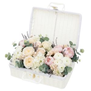 Biały kuferek dekoracyjny walizka 30x22 cm otwarty, wypełniony kompozycją z kwiatów i eukaliptusa ze złotym zapięciem.