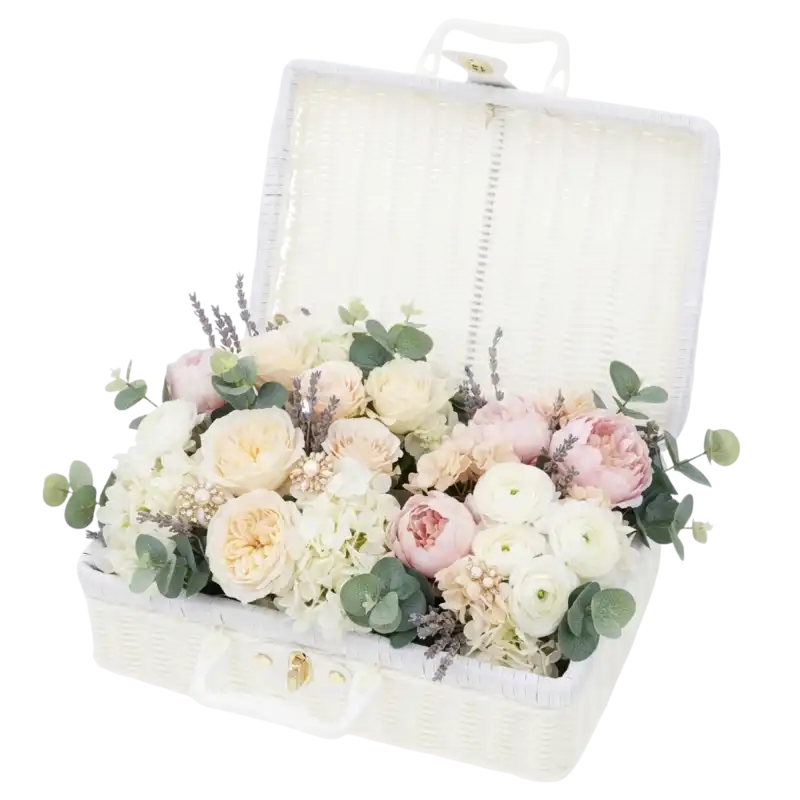 Biały kuferek dekoracyjny walizka 30x22 cm otwarty, wypełniony kompozycją z kwiatów i eukaliptusa ze złotym zapięciem.